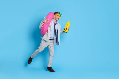 Şişme yüzüklü bir iş adamı, komik güneş gözlükleri ve açık mavi arka planda paletler, metin için yer