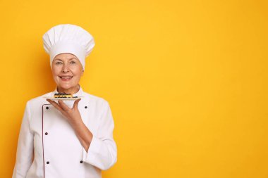 Turuncu arka planı olan profesyonel pasta şefi. Metin için boşluk