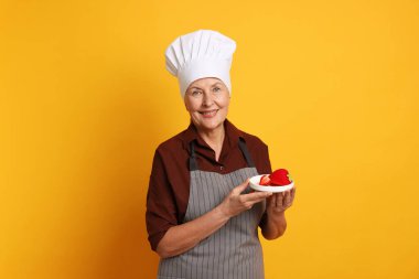 Turuncu arka planda tatlı yapan profesyonel bir şekerci.