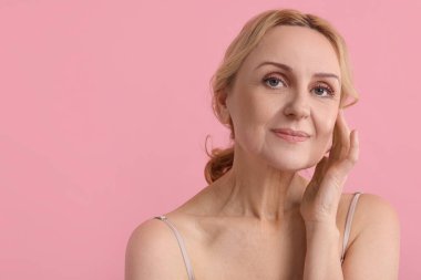 Pembe arka planda orta yaşlı güzel bir kadının portresi. Metin için boşluk