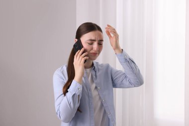 Stresli kadın, evdeki pencerenin yanındaki ruh sağlığı yardım hattını arıyor.