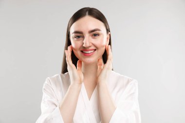 Gri arka planda sağlıklı ciltli gülümseyen kadın.