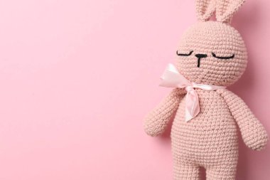 Pembe arka planda sevimli örülmüş oyuncak tavşan. Metin için boşluk