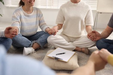 Grup psikoterapi seansı sırasında el ele tutuşan insanlar kapalı mekanda, yakın çekim