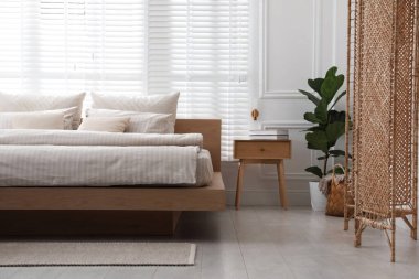 Rahat yatak, komodin ve bitki şık bir odada. İç tasarım