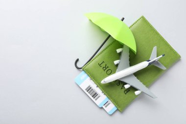 Seyahat sigortası. Uçak modeli, pasaport, küçük şemsiye ve açık gri arka planda biletler. Metin için boşluk