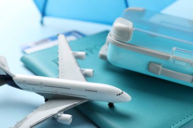 Seyahat sigortası. Uçak modeli, pasaport, bavul ve bilet açık mavi arka planda, yakın plan.