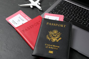 Pasaportlar, uçuş biletleri, uçak modeli ve laptop siyah masada, yakın plan.