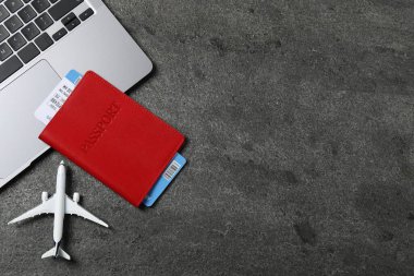 Pasaport, uçuş bileti, uçak modeli ve gri masada dizüstü bilgisayar, düz konum. Metin için boşluk