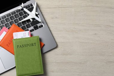 Pasaportlar, uçuş biletleri, uçak modeli ve dizüstü bilgisayar ahşap masa, üst manzara. Metin için boşluk