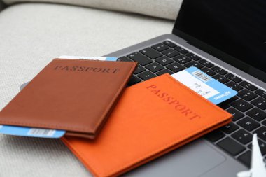 Pasaportlar, uçuş biletleri ve dizüstü bilgisayar koltukta.