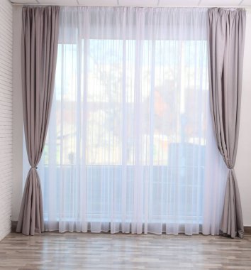 Boş odada zarif perdeleri olan pencere.