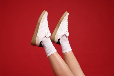 Kırmızı arka planda şık ayakkabılar giyen kadın, yakın plan.