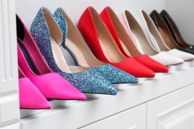 Ayakkabı deposu. İçerideki raflarda farklı yüksek topuklu ayakkabılar, yakın plan.