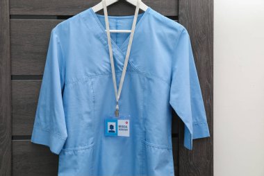 İçerideki askıda rozeti olan sağlık çalışanı üniforması.