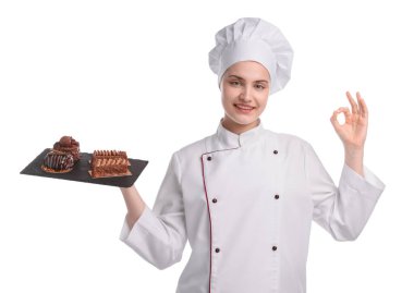 Üniformalı mutlu pastacı lezzetli çikolatalı tatlılar tutuyor ve beyaz arka planda iyi bir jest yapıyor.