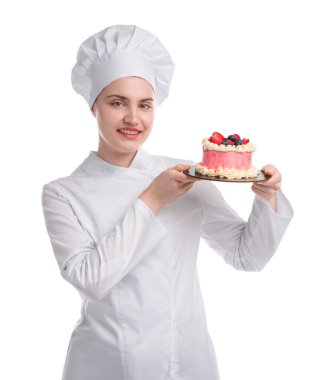 Üniformalı mutlu pastacı elinde beyaz arka planda böğürtlenli kek tutuyor.