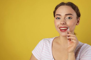 Mutlu kadın açık yeşil arka planda cımbızla bıyıklarını yoluyor. Metin için boşluk