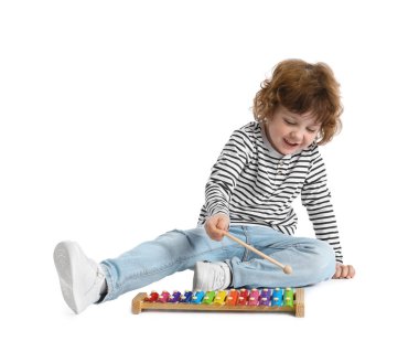 Beyaz arka planda oyuncak ksilofon çalan sevimli küçük çocuk.