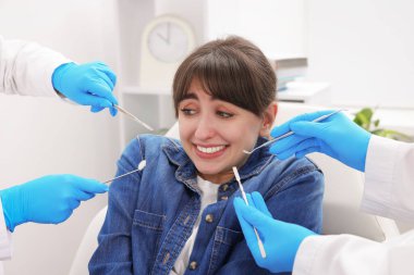 Klinikte dişçi ve asistanla randevusu olan korkmuş bir kadın.