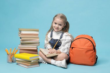 Sırt çantası ve açık mavi arka plan kitapları olan liseli kız.