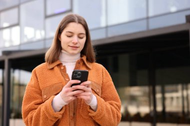 Güzel genç kız dışarıda akıllı telefon kullanıyor, mesaj için yer var.