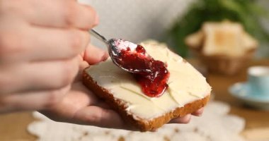 Masada yağlı tost üzerine reçel koyan kadın, yakın plan.