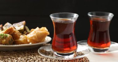 Geleneksel Türk çayı cam bardaklarda ve tatlılar beyaz masada, yakın plan