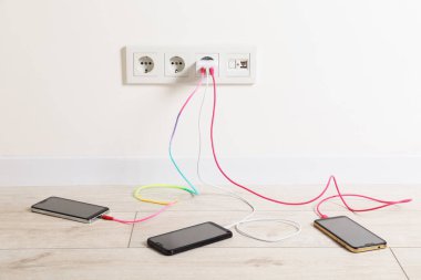 Kabloları elektrik prizine takılı USB adaptörü içeride farklı cihazları şarj ediyor