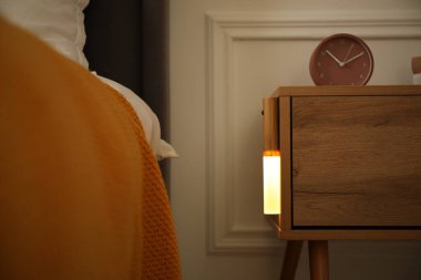 Parlak modern LED lamba ahşap komodinin üzerinde kapalı, yakın plan