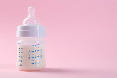 Pembe arka planda sütle beslenme şişesi, metin için boşluk