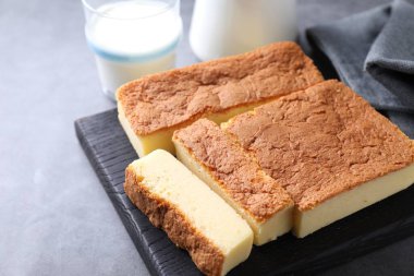 Tasty Japanese Castella sponge cake and milk on grey table, closeup