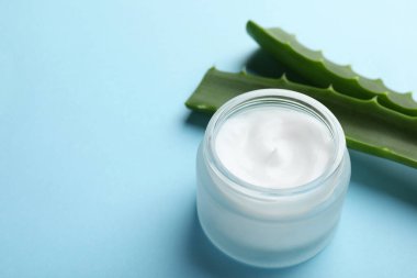 Açık mavi arkaplanda krema ve aloe yaprakları. Metin için boşluk