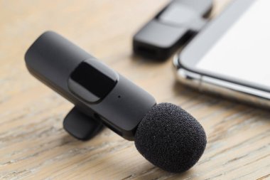Lavalier mikrofon ve ahşap masada kablosuz alıcısı olan akıllı telefon.