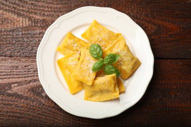 Ahşap masada parmesan peynirli ve fesleğenli lezzetli ravioli.