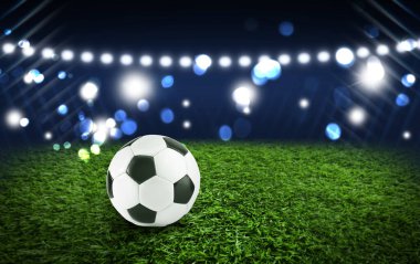 Futbol stadyumunda yeşil çimlerin üzerinde futbol topu, metin için alan