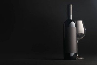 Siyah zemin üzerinde şarap ve cam şişesi, metin için boşluk