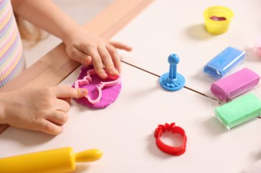 Motor beceri geliştirme. Masada renkli hamurla oynayan küçük kız, yakın plan.