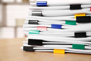 Kapalı alanda, ahşap masa üzerinde kağıt yaprakları ile renkli cilt ataçları