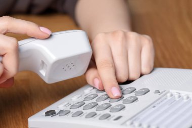 Ahşap masada telefonla arayan kadın, yakın plan.