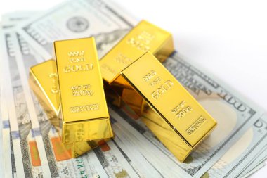 Parlak altın külçeler ve beyaz arka planda dolar banknotları, yakın plan