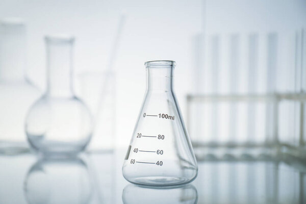 Пустая колба на поверхности зеркала на светлом фоне. Лабораторное оборудование