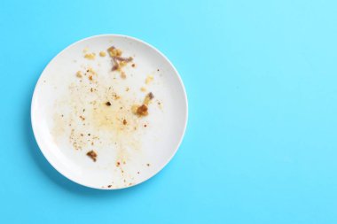 Açık mavi arka planda kirli bir tabak, üst manzara. Metin için boşluk