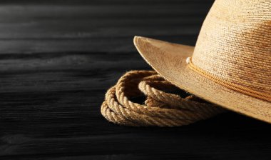 Siyah ahşap arka planda pamuk ip ve hasır şapka, yakın plan. Metin için boşluk