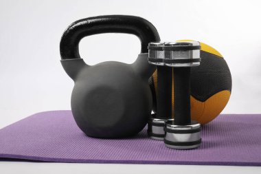 Kettlebell, dambıl ve spor topu beyaz arka planda fitness minderi