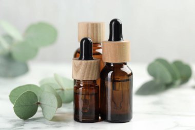 Gerekli yağ ve okaliptüs şişeleri beyaz mermer masa üzerinde, yakın çekim