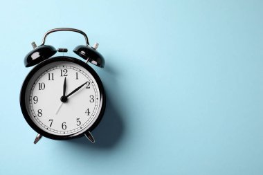 Açık mavi zemin üzerinde siyah alarm saati, üst manzara. Metin için boşluk