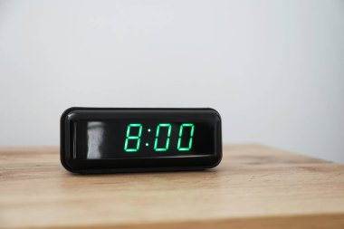 Dijital alarm saati, saat 8: 00 'de komodinin üzerinde, ışık arka planında.