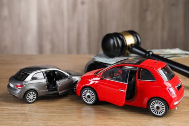 Motorlu taşıt kazası yasası. Gavel, para ve araba modelleri ahşap arka planda, yakın plan.
