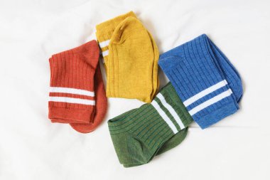 Beyaz battaniyede farklı yumuşak çoraplar, üst manzara.